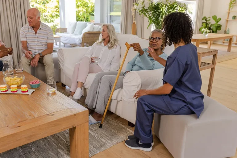 Caregiver visiting with older adults in a bright living room